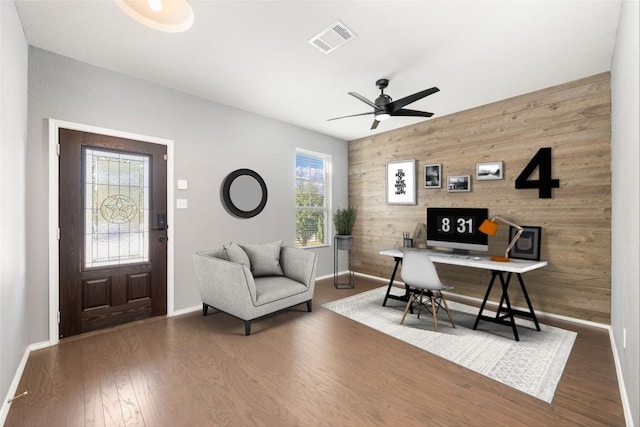 office with wooden walls, ceiling fan, and dark wood-type flooring