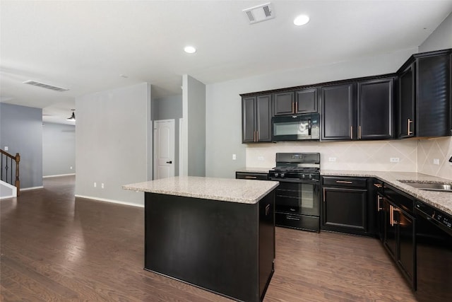 kitchen with a center island, backsplash, dark wood-type flooring, black appliances, and light stone countertops