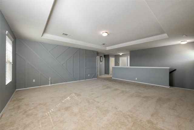 carpeted spare room featuring a raised ceiling and ornamental molding