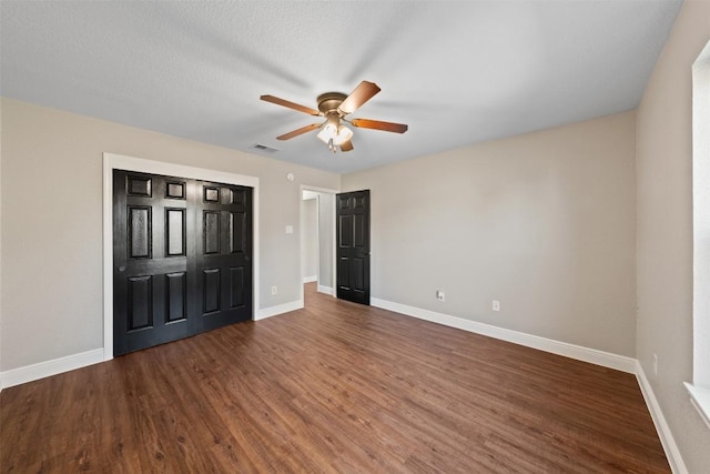 unfurnished bedroom featuring a textured ceiling, ceiling fan, and dark wood-type flooring