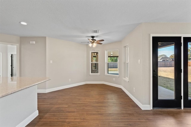 unfurnished dining area featuring a textured ceiling, ceiling fan, and dark wood-type flooring