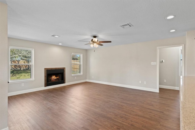 unfurnished living room featuring dark hardwood / wood-style floors, ceiling fan, and a textured ceiling