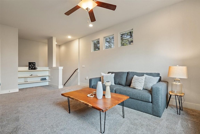 carpeted living room with built in shelves and ceiling fan