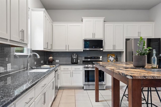 kitchen featuring appliances with stainless steel finishes, tasteful backsplash, white cabinetry, sink, and light tile patterned floors