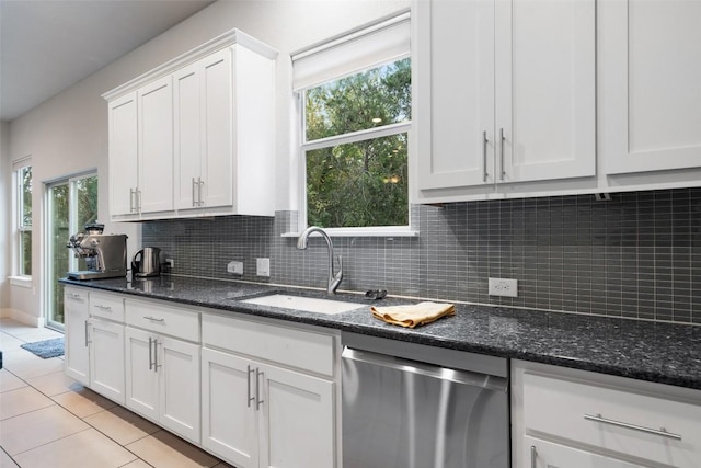 kitchen with light tile patterned floors, tasteful backsplash, stainless steel dishwasher, white cabinets, and a sink