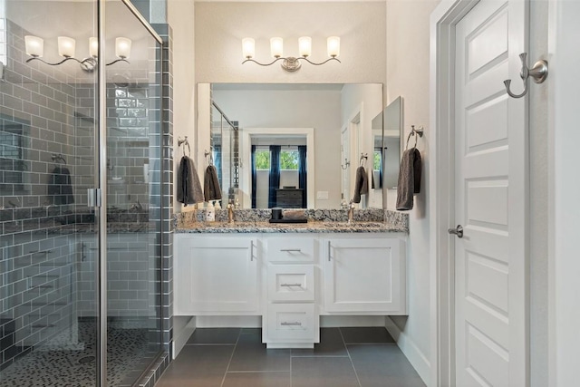 full bath with double vanity, a sink, a shower stall, tile patterned flooring, and baseboards