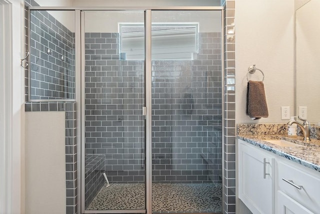 bathroom featuring a shower with door and vanity