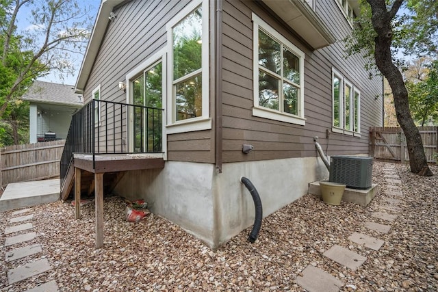 view of property exterior with central air condition unit and fence