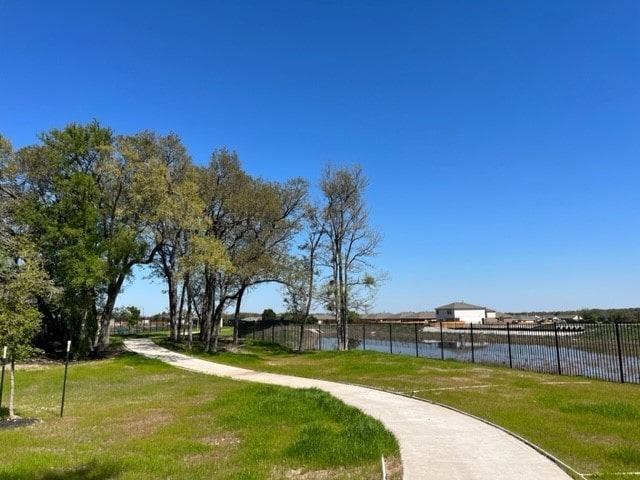 surrounding community with a water view and a lawn