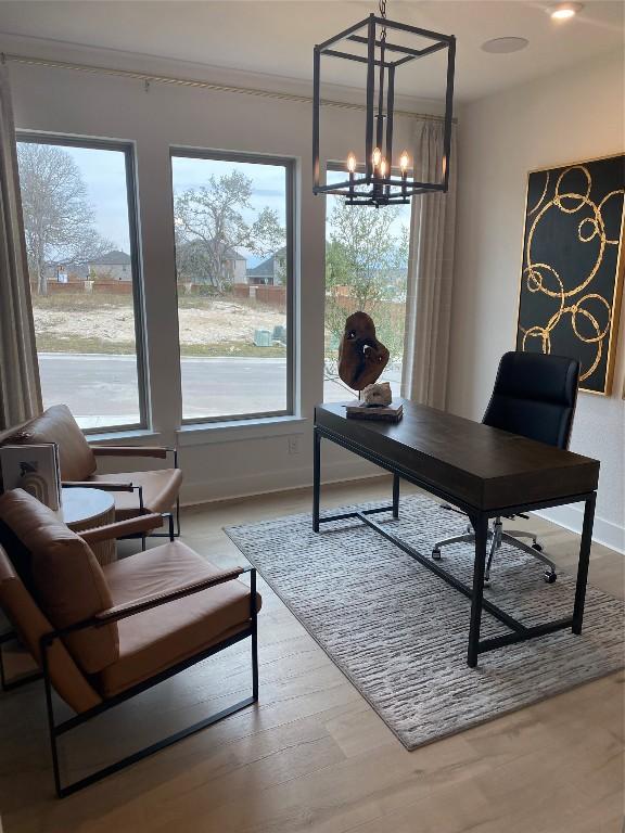 home office featuring light wood-type flooring and a notable chandelier