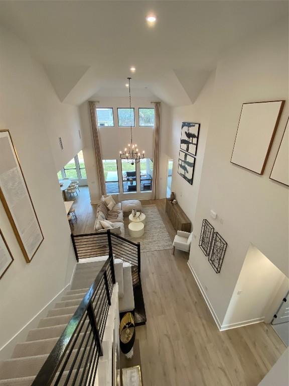 stairway featuring wood-type flooring, a high ceiling, and an inviting chandelier