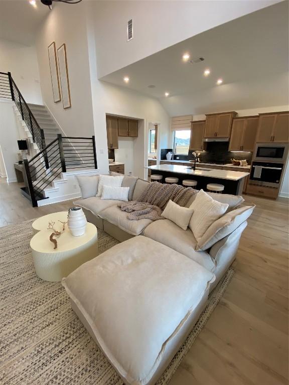 living room with light hardwood / wood-style flooring, a towering ceiling, and sink