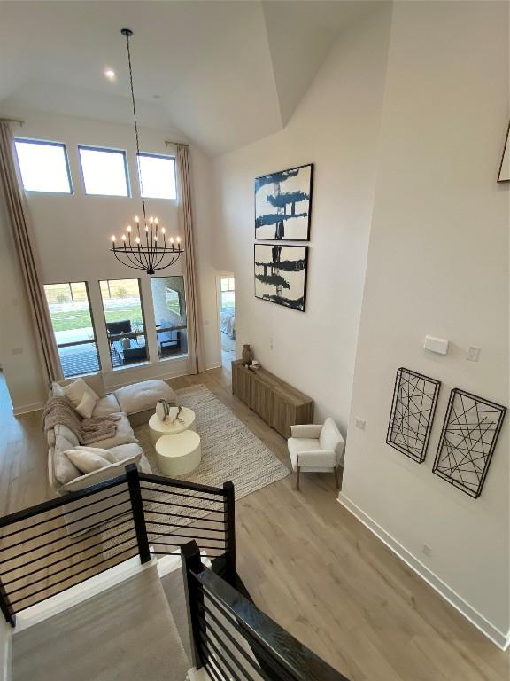 living room with hardwood / wood-style flooring, high vaulted ceiling, and an inviting chandelier