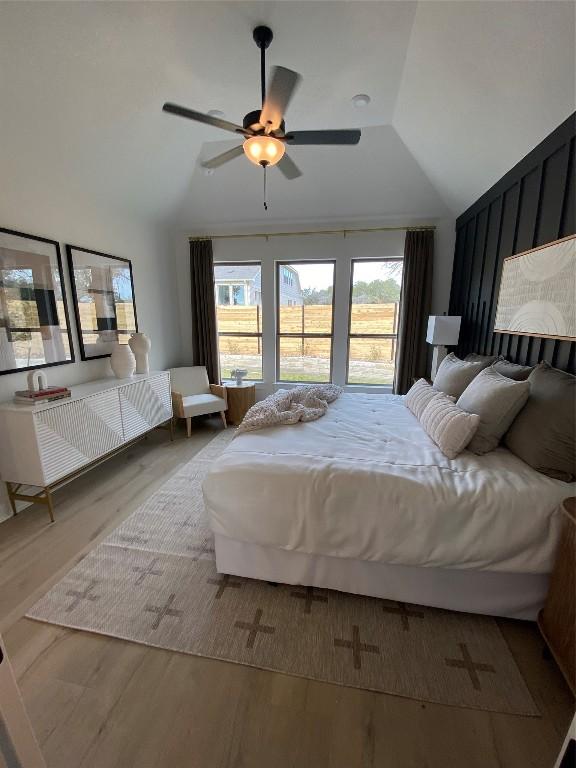 bedroom featuring multiple windows, ceiling fan, hardwood / wood-style floors, and vaulted ceiling