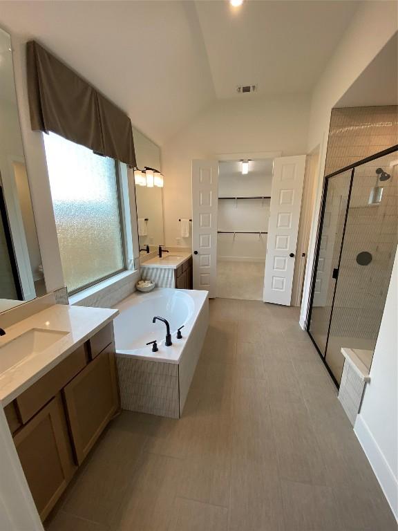 bathroom with shower with separate bathtub, vanity, and lofted ceiling