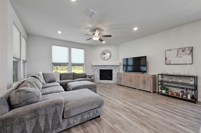 living room with ceiling fan, a fireplace, and light hardwood / wood-style floors