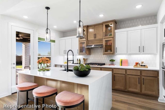 kitchen featuring a kitchen breakfast bar, dark hardwood / wood-style flooring, an island with sink, and hanging light fixtures