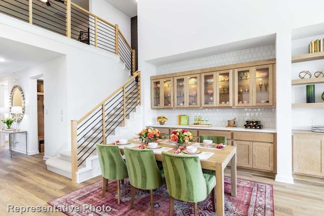 dining area with a towering ceiling and light hardwood / wood-style flooring