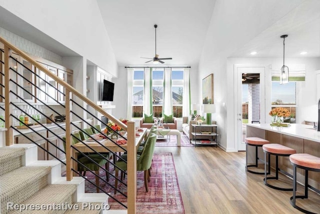 living room with ceiling fan, light hardwood / wood-style flooring, and high vaulted ceiling