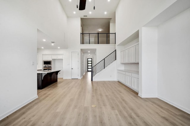 596 Biscayne Bay Bnd, Kyle, TX 78640 - unfurnished living room with stairs, a towering ceiling, and light wood-style floors