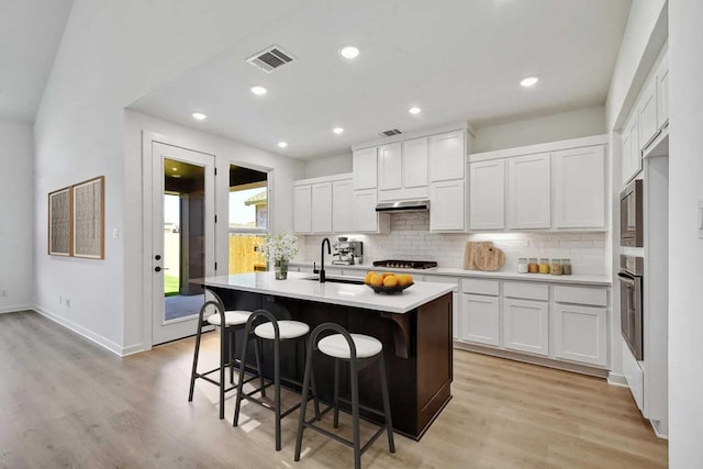 596 Biscayne Bay Bnd, Kyle, TX 78640 - kitchen with decorative backsplash, light countertops, a kitchen bar, under cabinet range hood, and visible vents