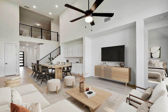 596 Biscayne Bay Bnd, Kyle, TX 78640 - living area with stairway, a ceiling fan, light wood-type flooring, a high ceiling, and visible vents