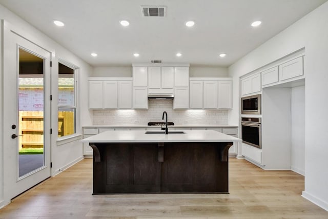 596 Biscayne Bay Bnd, Kyle, TX 78640 - kitchen with stainless steel oven, a kitchen island with sink, light countertops, and a sink