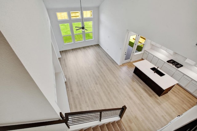 596 Biscayne Bay Bnd, Kyle, TX 78640 - unfurnished living room featuring baseboards, a ceiling fan, wood finished floors, and a high ceiling