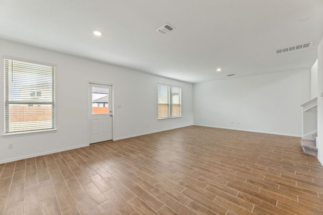 unfurnished room featuring visible vents, recessed lighting, stairway, and wood finished floors