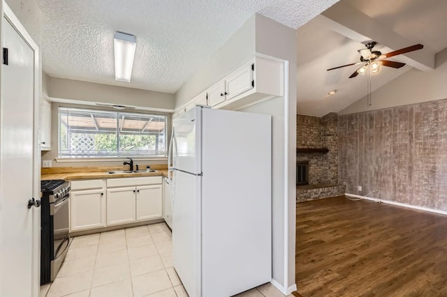 kitchen with white cabinets, white fridge, lofted ceiling, and stainless steel range with gas stovetop