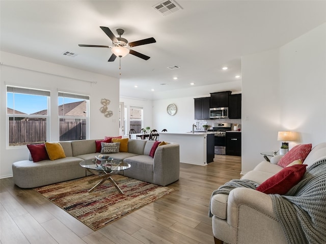 living room with light hardwood / wood-style flooring and ceiling fan