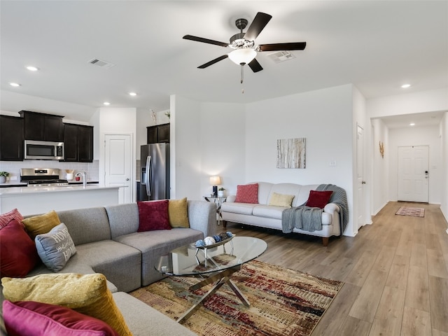 living room featuring ceiling fan and light hardwood / wood-style floors