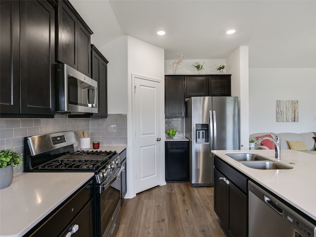 kitchen featuring tasteful backsplash, sink, stainless steel appliances, and wood-type flooring