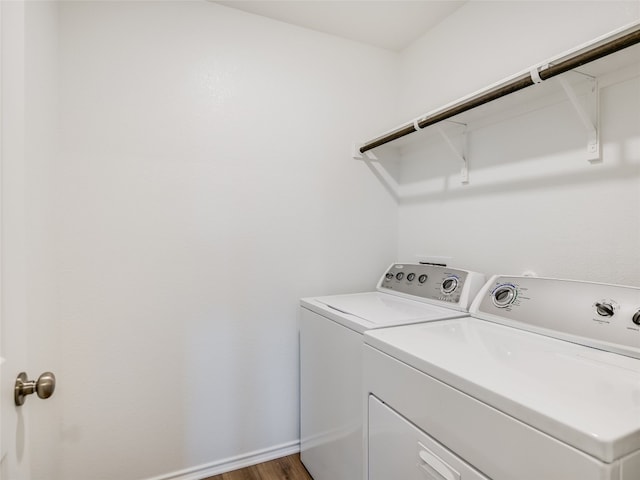 clothes washing area with washer and dryer and dark wood-type flooring