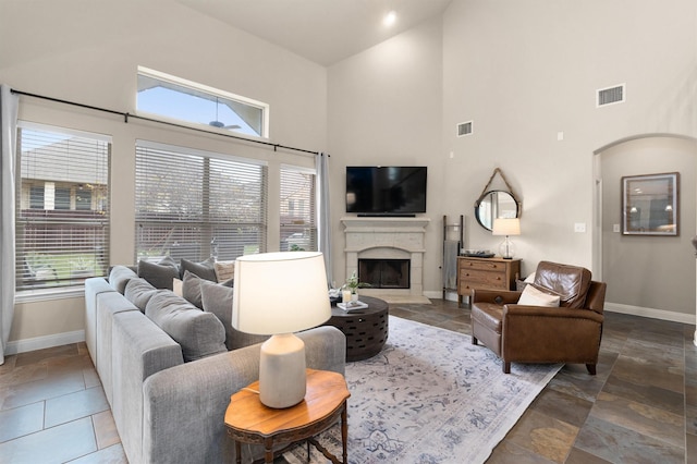 living room with a fireplace and a towering ceiling