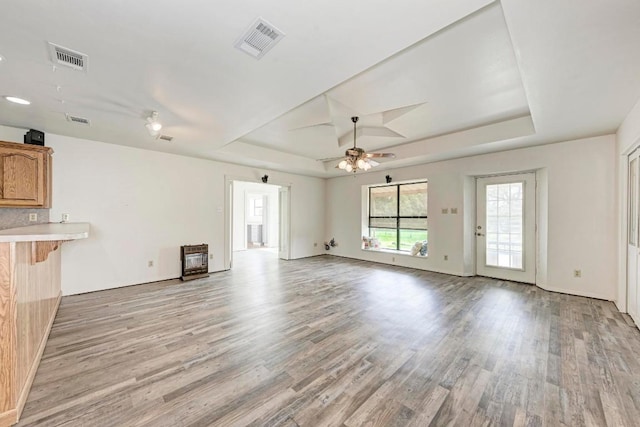 unfurnished living room with a tray ceiling, ceiling fan, and light hardwood / wood-style floors