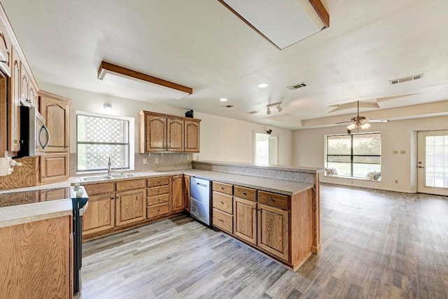 kitchen featuring ceiling fan, sink, light hardwood / wood-style flooring, kitchen peninsula, and appliances with stainless steel finishes