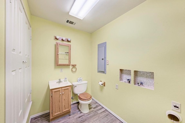 bathroom with hardwood / wood-style floors, vanity, toilet, and electric panel