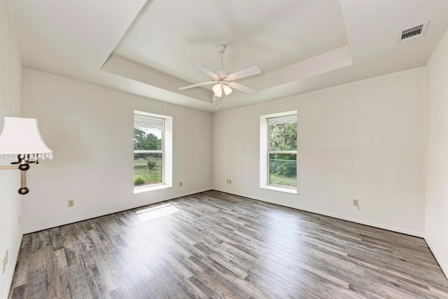 empty room featuring wood-type flooring, a raised ceiling, and ceiling fan