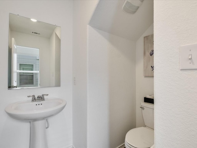 bathroom featuring vaulted ceiling, toilet, and sink