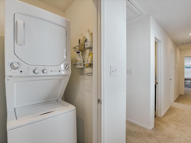 clothes washing area with light carpet and stacked washer / drying machine