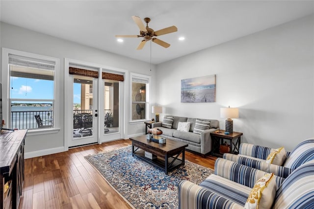 living room featuring hardwood / wood-style flooring, ceiling fan, and a water view