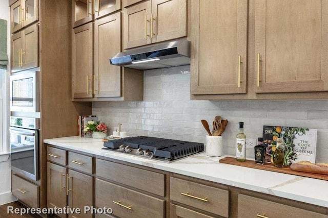 kitchen featuring decorative backsplash, light stone counters, and stainless steel appliances