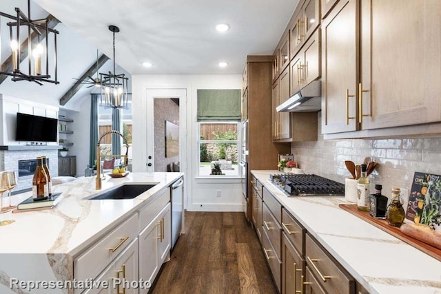 kitchen featuring sink, decorative light fixtures, appliances with stainless steel finishes, dark hardwood / wood-style flooring, and light stone counters