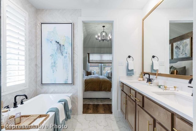 bathroom with a chandelier, vanity, a bathing tub, and a healthy amount of sunlight