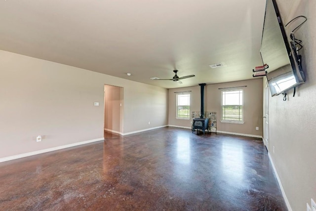 unfurnished living room with ceiling fan and a wood stove