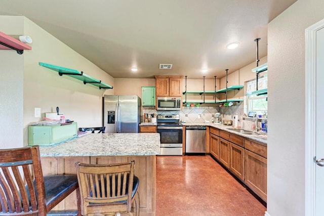 kitchen featuring light stone countertops, sink, a breakfast bar area, decorative backsplash, and appliances with stainless steel finishes