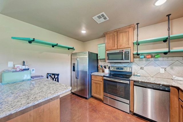 kitchen featuring concrete flooring, appliances with stainless steel finishes, tasteful backsplash, and light stone counters