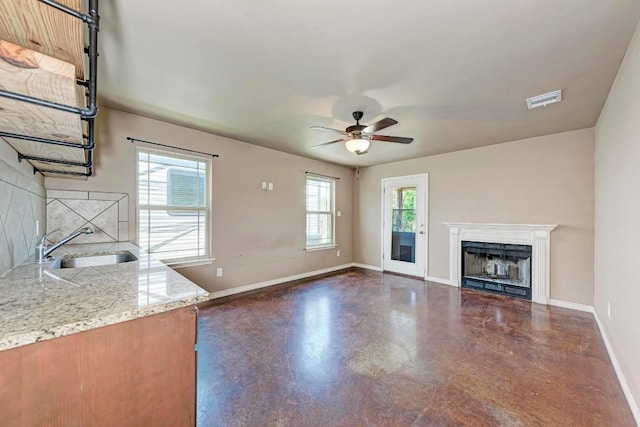 unfurnished living room featuring ceiling fan and sink