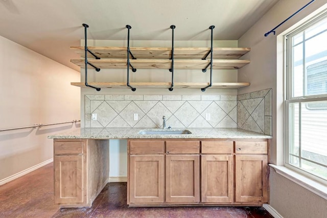 kitchen featuring light stone counters, sink, a wealth of natural light, and tasteful backsplash